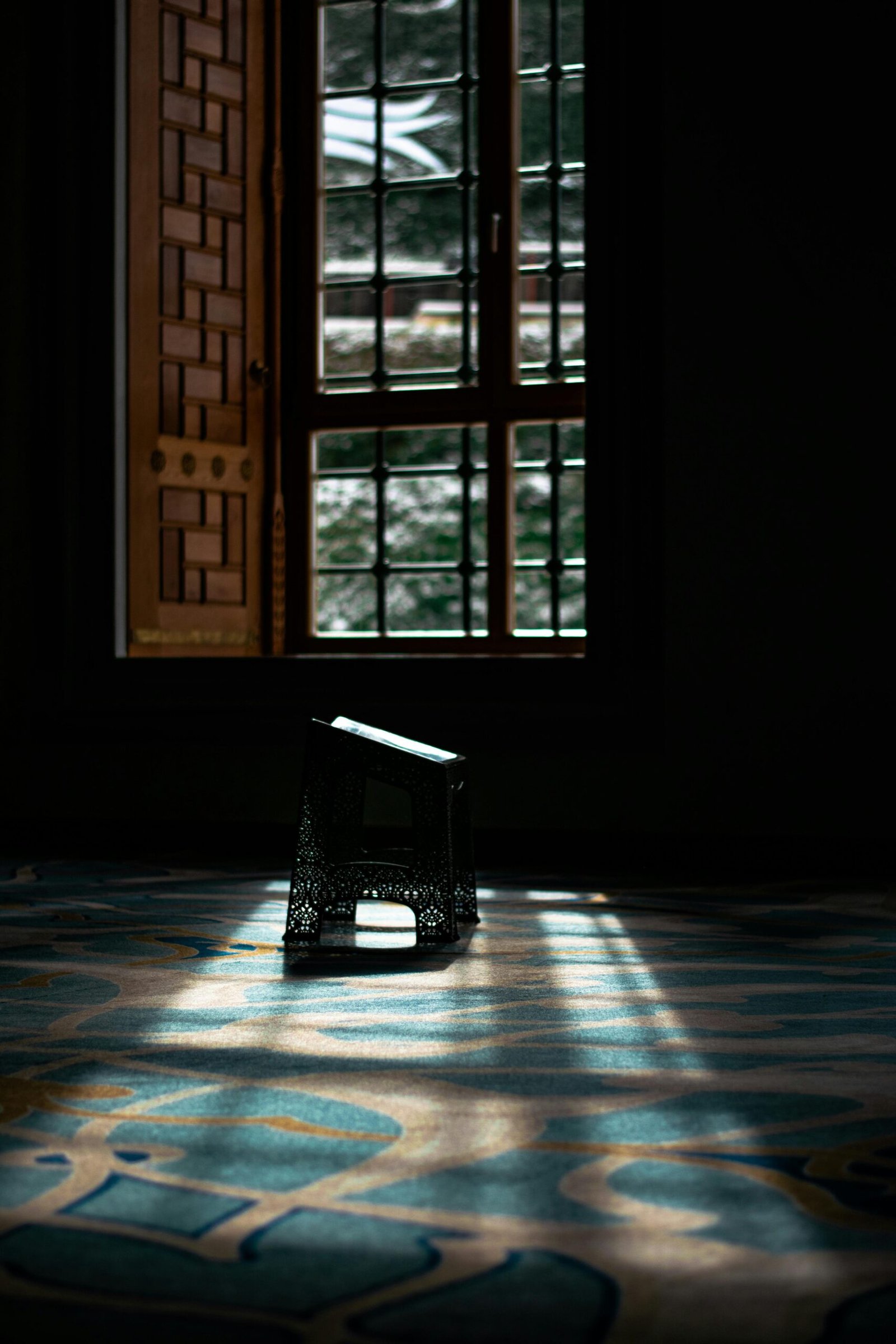 Home Sunlight casts shadows in a serene mosque setting with a Quran stand.